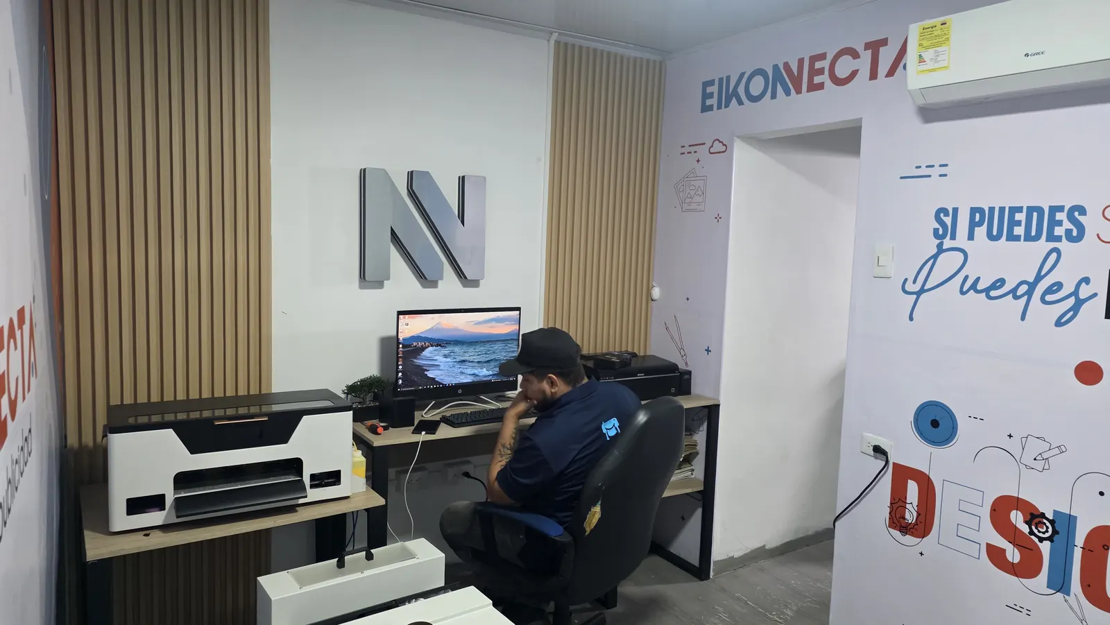 Taller de producción de EIKONECTA en Sincelejo con impresora DTF, estación de diseño y murales de la marca